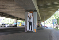 Plakat mit einem Mann, der die Arme hochstreckt, unter einer Unterführung