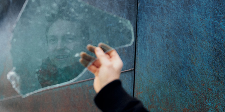 Ein Forscher hält eine große Glasschreibe in seiner Hand, in der sich sein Gesicht spiegelt.