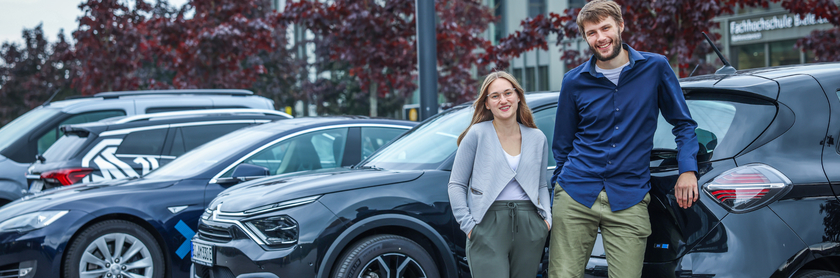 Die wissenschaftlichen Mitarbeiter Melina Gurcke und Lars Quakernack stehen vor verschiedenen E-Fahrzeugen