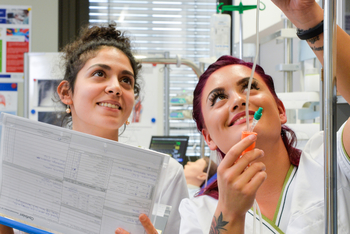 Zwei Studentinnen befinden sich im Skills Lab und halten einen intravenösen Zugang in der Hand.